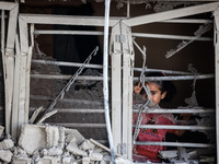 A Palestinian girl is looking out the window of a damaged apartment block following overnight Israeli strikes in Nuseirat refugee camp in th...