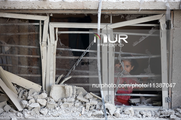 A Palestinian girl is looking out the window of a damaged apartment block following overnight Israeli strikes in Nuseirat refugee camp in th...