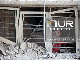 A Palestinian girl is looking out the window of a damaged apartment block following overnight Israeli strikes in Nuseirat refugee camp in th...