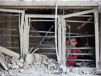 A Palestinian girl is looking out the window of a damaged apartment block following overnight Israeli strikes in Nuseirat refugee camp in th...