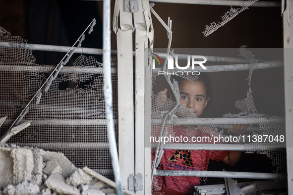 A Palestinian girl is looking out the window of a damaged apartment block following overnight Israeli strikes in Nuseirat refugee camp in th...