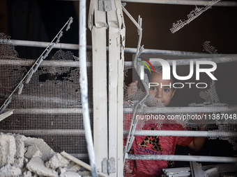 A Palestinian girl is looking out the window of a damaged apartment block following overnight Israeli strikes in Nuseirat refugee camp in th...