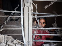 A Palestinian girl is looking out the window of a damaged apartment block following overnight Israeli strikes in Nuseirat refugee camp in th...