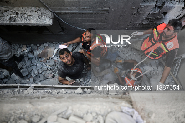 Palestinian civil defense staff are bringing out the body of a man after he was pulled out from under the rubble of a destroyed house after...