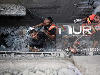 Palestinian civil defense staff are bringing out the body of a man after he was pulled out from under the rubble of a destroyed house after...