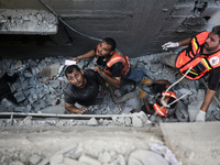 Palestinian civil defense staff are bringing out the body of a man after he was pulled out from under the rubble of a destroyed house after...