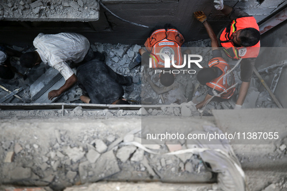 Palestinian civil defense staff are bringing out the body of a man after he was pulled out from under the rubble of a destroyed house after...