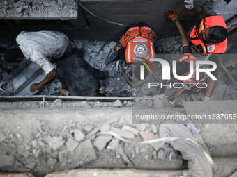 Palestinian civil defense staff are bringing out the body of a man after he was pulled out from under the rubble of a destroyed house after...