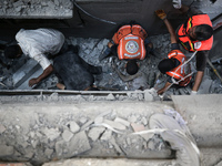 Palestinian civil defense staff are bringing out the body of a man after he was pulled out from under the rubble of a destroyed house after...