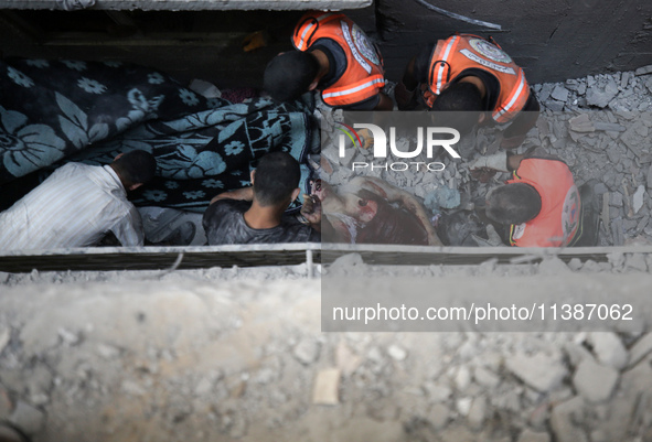 Palestinian civil defense staff are bringing out the body of a man after he was pulled out from under the rubble of a destroyed house after...