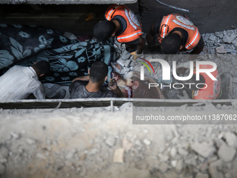 Palestinian civil defense staff are bringing out the body of a man after he was pulled out from under the rubble of a destroyed house after...