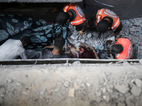 Palestinian civil defense staff are bringing out the body of a man after he was pulled out from under the rubble of a destroyed house after...