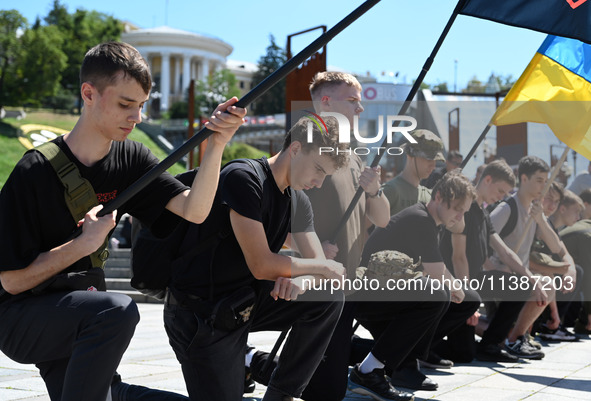 People are kneeling during a funeral ceremony for British volunteer and combat medic Peter Fouche at Independence Square in Kyiv, Ukraine, o...