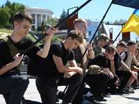 People are kneeling during a funeral ceremony for British volunteer and combat medic Peter Fouche at Independence Square in Kyiv, Ukraine, o...