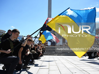 People are kneeling during a funeral ceremony for British volunteer and combat medic Peter Fouche at Independence Square in Kyiv, Ukraine, o...