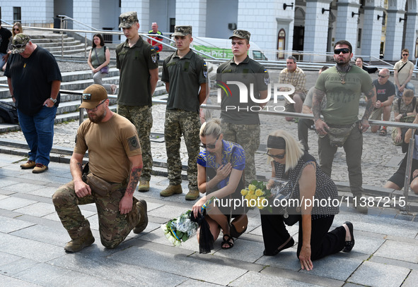 People are kneeling during a funeral ceremony for British volunteer and combat medic Peter Fouche at Independence Square in Kyiv, Ukraine, o...