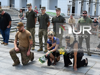 People are kneeling during a funeral ceremony for British volunteer and combat medic Peter Fouche at Independence Square in Kyiv, Ukraine, o...