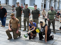 People are kneeling during a funeral ceremony for British volunteer and combat medic Peter Fouche at Independence Square in Kyiv, Ukraine, o...