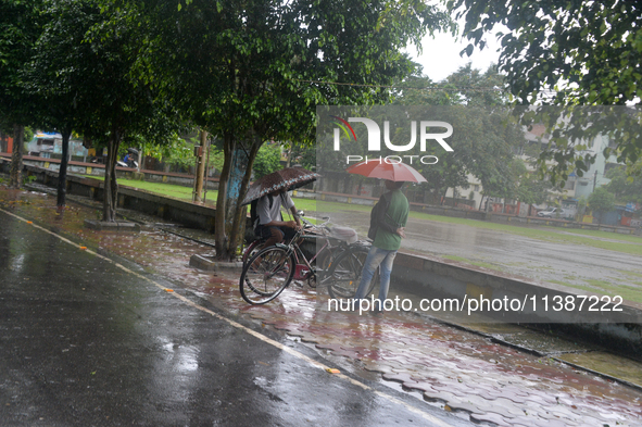 People are being seen during a continuous rainfall in Siliguri, India, on July 6, 2024. 