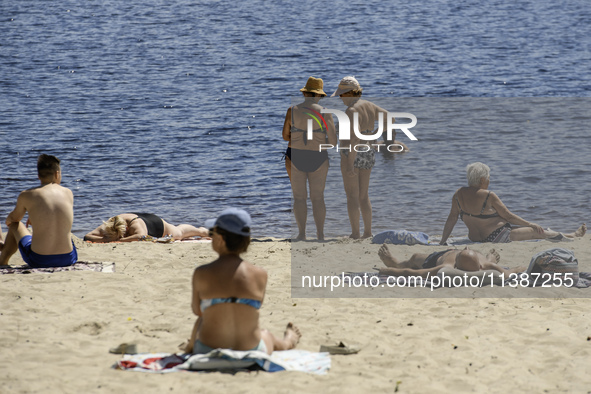 People are relaxing on the beach on the banks of the Dnipro River in Kyiv, Ukraine, on July 06, 2024. Heatwaves of up to 40 degrees Celsius...