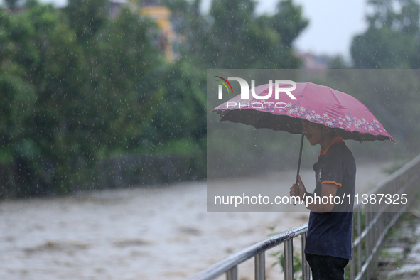 A Nepali citizen is standing on the embankments of the overflowing Bagmati river in Lalitpur, Nepal, on July 6, 2024. With the onset of the...