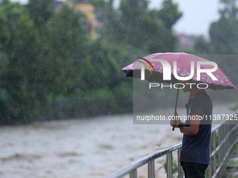 A Nepali citizen is standing on the embankments of the overflowing Bagmati river in Lalitpur, Nepal, on July 6, 2024. With the onset of the...