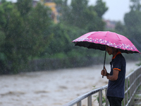 A Nepali citizen is standing on the embankments of the overflowing Bagmati river in Lalitpur, Nepal, on July 6, 2024. With the onset of the...