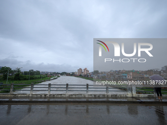 A Nepali citizen is wearing an umbrella and watching the rising level of the Bagmati River in Lalitpur, Nepal, on July 6, 2024. With the ons...