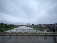 A Nepali citizen is wearing an umbrella and watching the rising level of the Bagmati River in Lalitpur, Nepal, on July 6, 2024. With the ons...