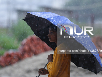 A Nepali boy is wearing an umbrella in Lalitpur, Nepal, on July 6, 2024. With the onset of the monsoon in Nepal about a month ago, the Kathm...