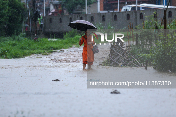 A Nepali woman is wading through a river that has burst its embankment and flowed into the residential areas in Bhaktapur, Nepal, on July 6,...