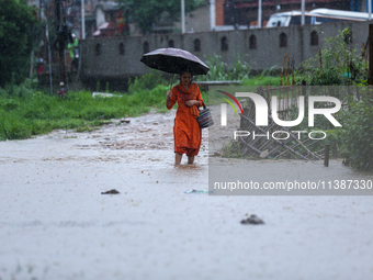 A Nepali woman is wading through a river that has burst its embankment and flowed into the residential areas in Bhaktapur, Nepal, on July 6,...