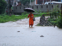 A Nepali woman is wading through a river that has burst its embankment and flowed into the residential areas in Bhaktapur, Nepal, on July 6,...