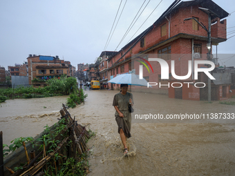 A Nepali woman is wading through a river that has burst its embankment and flowed into the residential areas in Bhaktapur, Nepal, on July 6,...