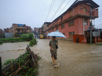 A Nepali woman is wading through a river that has burst its embankment and flowed into the residential areas in Bhaktapur, Nepal, on July 6,...