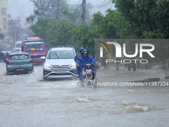 Vehicles are wading through a flooded road in Lalitpur, Nepal, on July 6, 2024. (