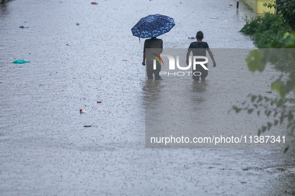 Dissidents in a slum area of Kathmandu are wading through the water in Kathmandu, Nepal, on July 6, 2024. 