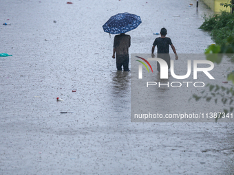 Dissidents in a slum area of Kathmandu are wading through the water in Kathmandu, Nepal, on July 6, 2024. (