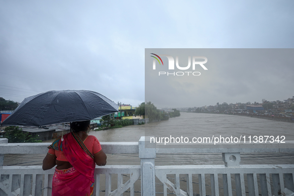 A Nepali woman is watching the rising level of the Bagmati River in Kathmandu, Nepal, on July 6, 2024. 