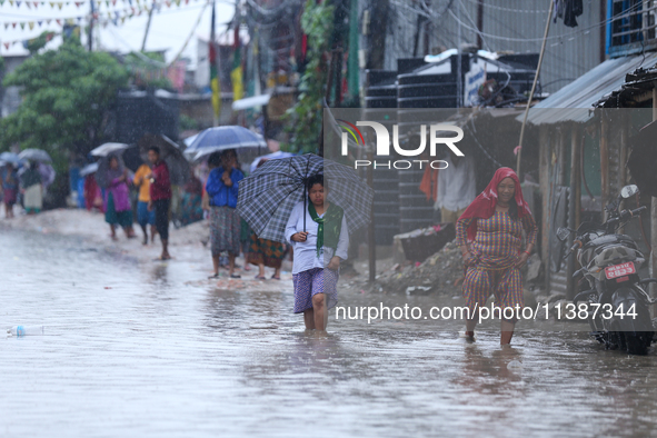 People are wading through the flood in a slum in Kathmandu, Nepal, on July 6, 2024 