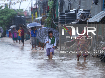 People are wading through the flood in a slum in Kathmandu, Nepal, on July 6, 2024 (