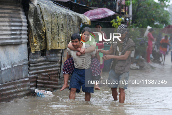 A man in Nepal is carrying a member of his family who is under a diagnosis while wading through the flood in Kathmandu, Nepal, on July 6, 20...