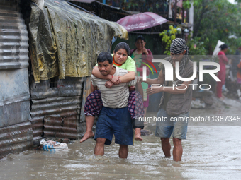 A man in Nepal is carrying a member of his family who is under a diagnosis while wading through the flood in Kathmandu, Nepal, on July 6, 20...