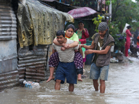 A man in Nepal is carrying a member of his family who is under a diagnosis while wading through the flood in Kathmandu, Nepal, on July 6, 20...