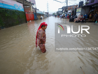 A Nepali woman is wading through the flood in Kathmandu, Nepal, on July 6, 2024. (