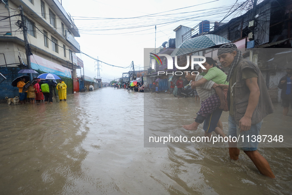 A Nepali man is carrying a member of his family who is under a diagnosis while wading through the flood in Kathmandu, Nepal, on July 6, 2024...