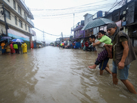 A Nepali man is carrying a member of his family who is under a diagnosis while wading through the flood in Kathmandu, Nepal, on July 6, 2024...