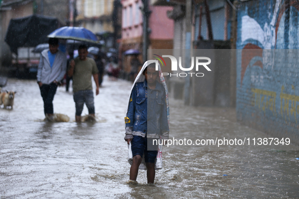 A Nepali boy is covering himself with a sack during the heavy rains in Nepal, on July 6, 2024. 