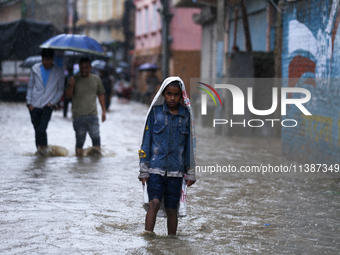 A Nepali boy is covering himself with a sack during the heavy rains in Nepal, on July 6, 2024. (