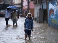 A Nepali boy is covering himself with a sack during the heavy rains in Nepal, on July 6, 2024. (